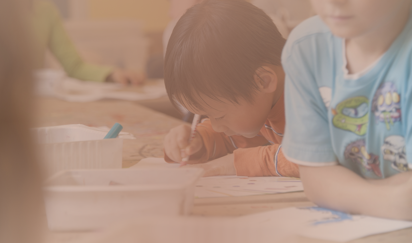A boy drawing at a table with friends