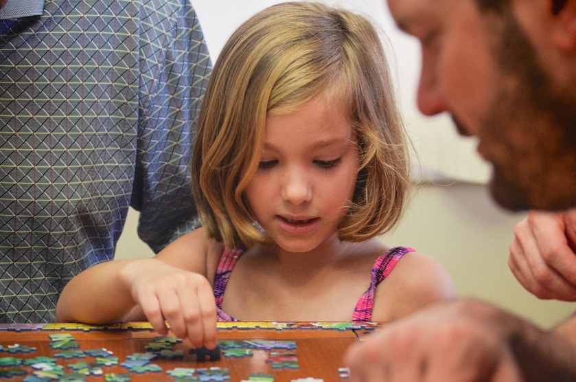 A girl playing a jigsaw puzzle with her father