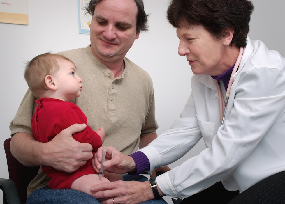 A doctor giving a young child an injection while a parent holds them