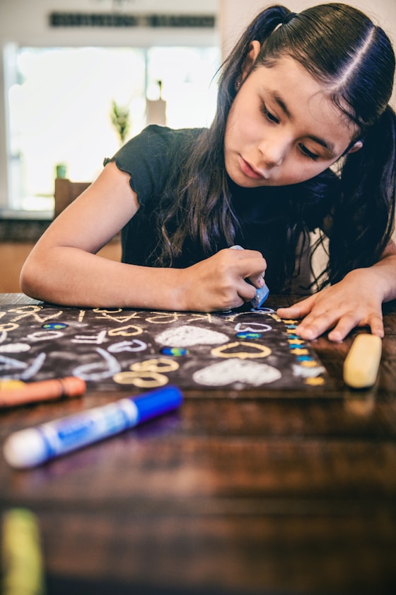 A girl writing on a chalkboard with colourful chalk