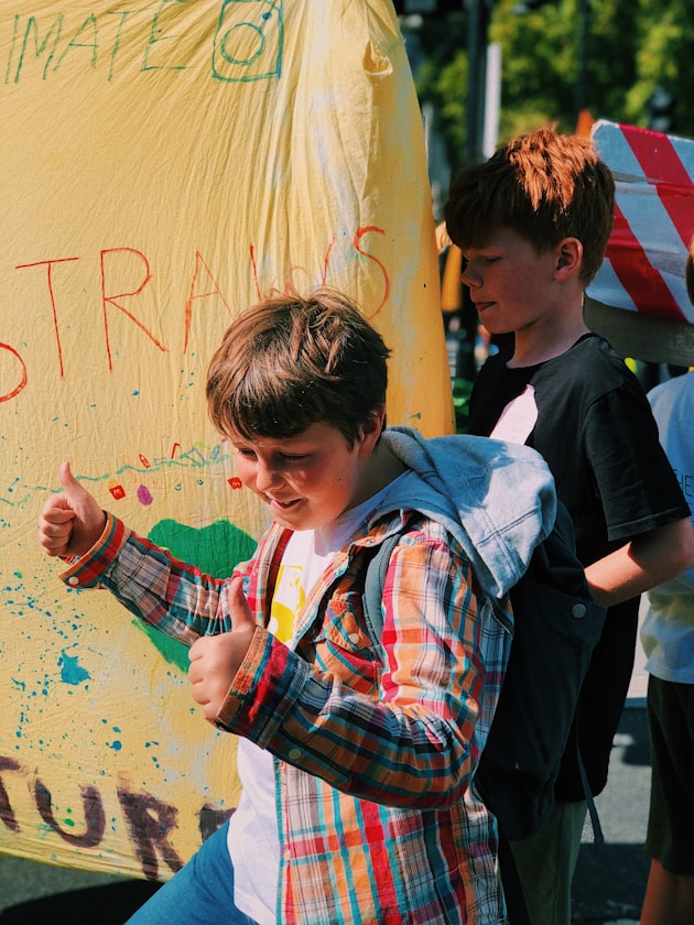 A boy giving a thumbs up in front of a painted banner