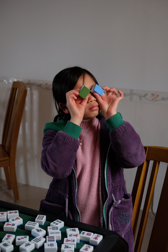 A girl holding coloured blocks over her eyes
