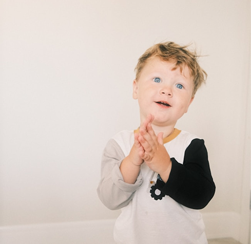 A toddler clapping their hands while wearing a cast