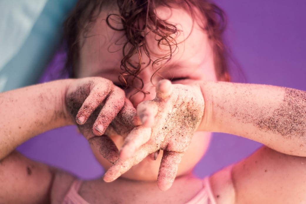 A child's sand-covered hands forming a heart shape