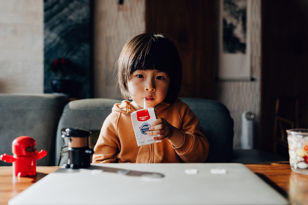A girl drinking from a juice pouch at a table
