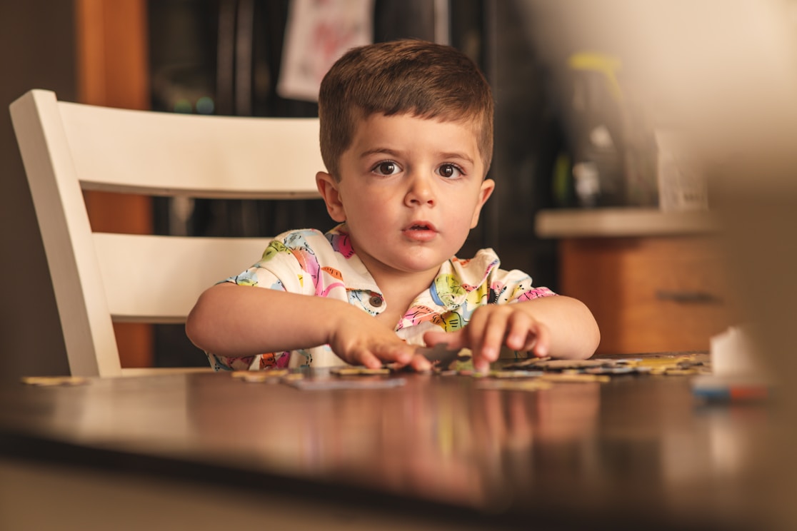 A boy sitting at a table with puzzle pieces