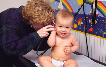 A clinician gently examining a baby's ear during a check-up