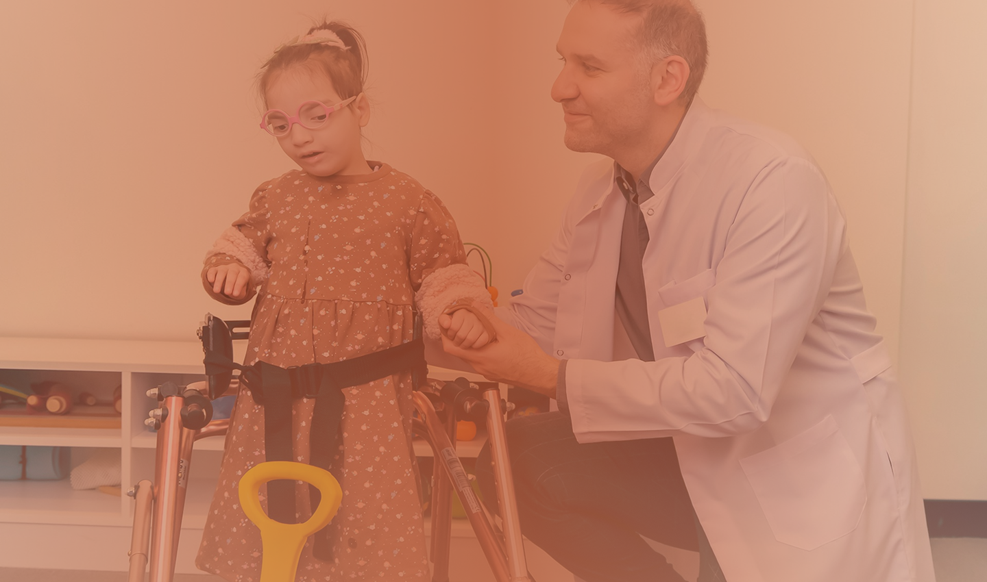 A doctor helping a young girl with a walking frame at Hiba by Anthalora