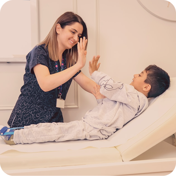 A nurse high-fiving a young boy in a hospital bed at Hiba by Anthalora