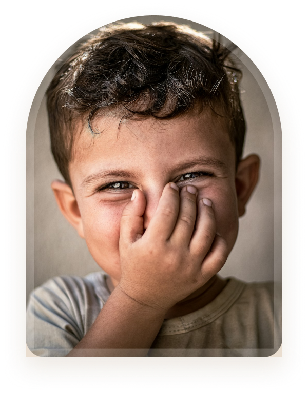 A boy laughing with his hand covering part of his face