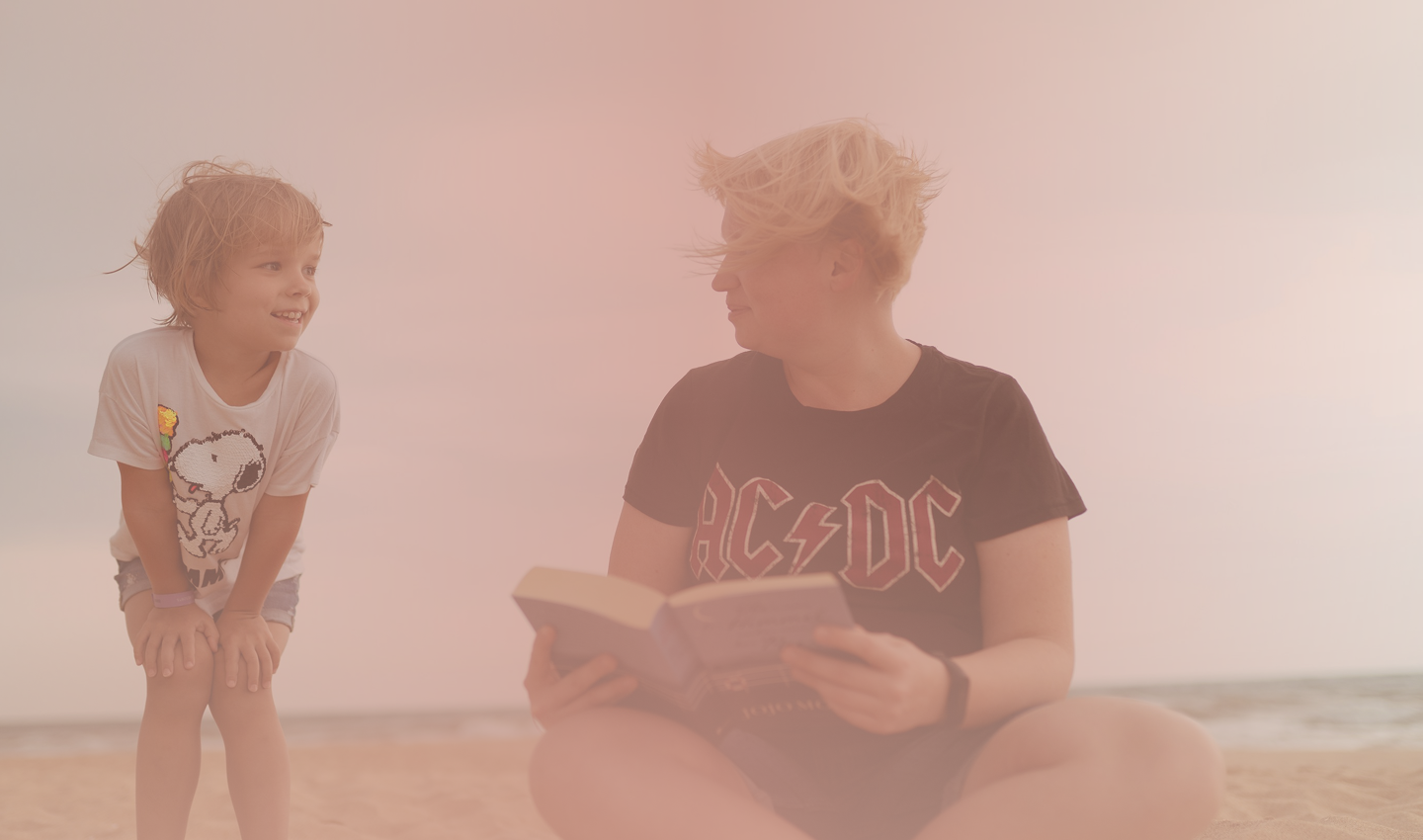 A mother reading a book with her son on the beach