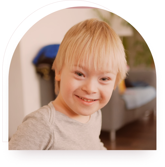 A boy with Down syndrome smiling brightly indoors