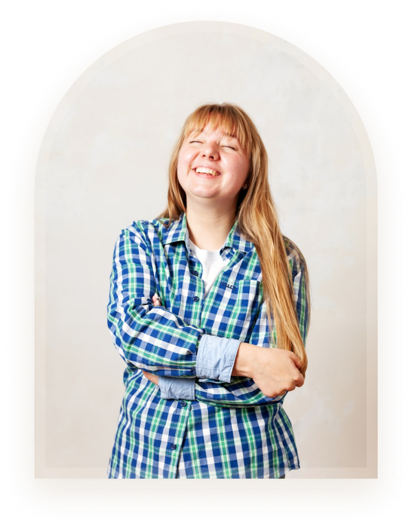 A young woman laughing joyfully with her arms crossed