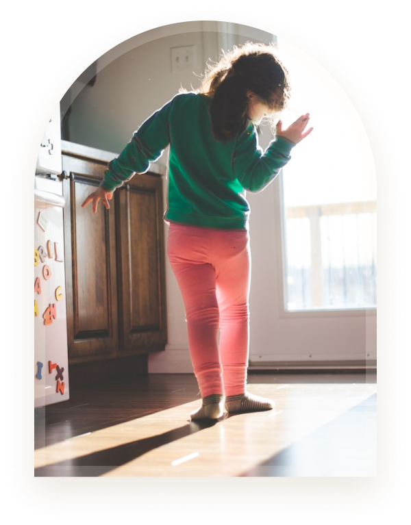 A girl balancing carefully on a sunlit kitchen floor
