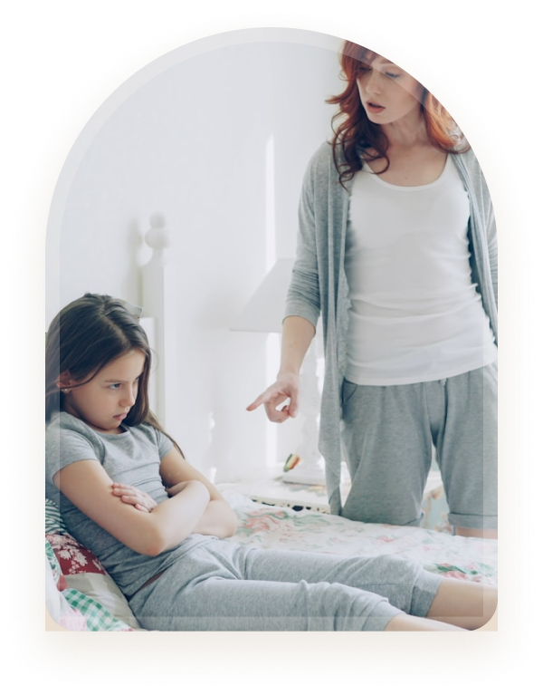 A mother speaking with her daughter who is sitting on a bed