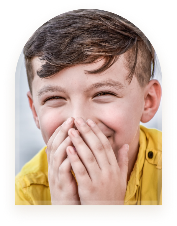 A boy laughing with his hands covering his mouth