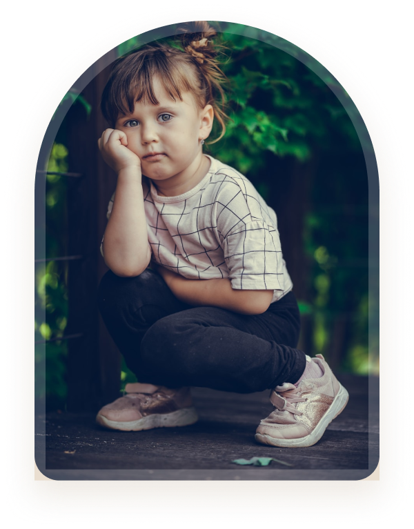 A girl crouching outdoors resting her chin on her hand