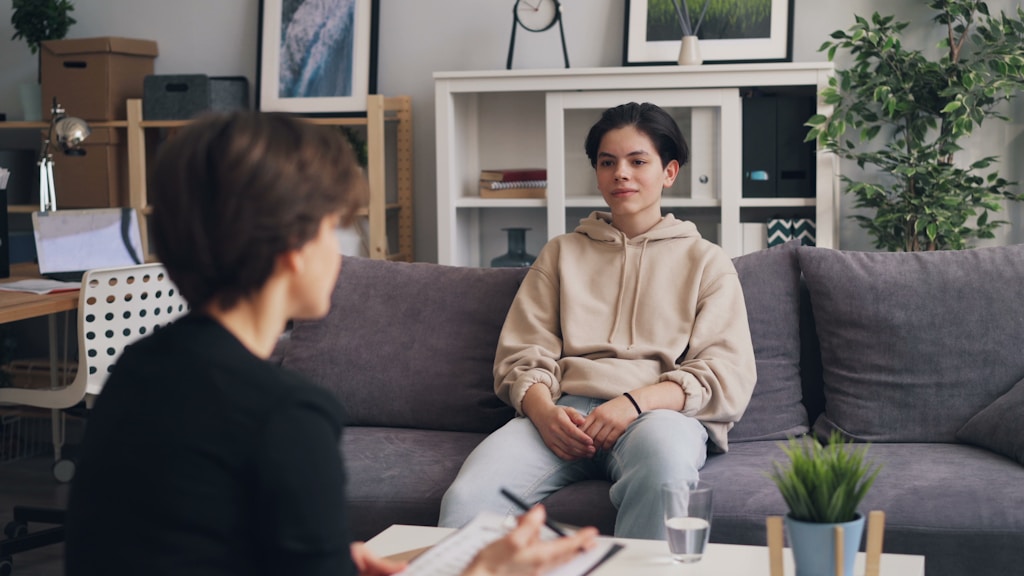 A clinician sitting with a young person during a therapy session