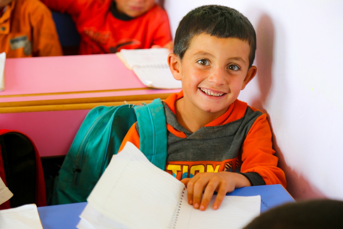 A smiling boy at his school desk