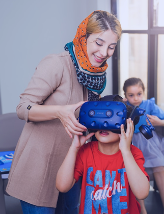 A child wearing a VR headset with support from a Hiba team member